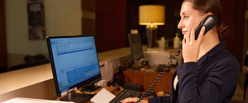 Hotel receptionist speaking on the phone at front desk – MSS Electronics