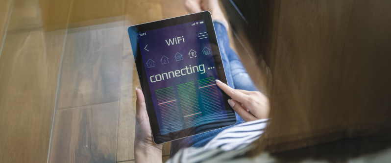 Woman holding a tablet while connecting to a Wi-Fi network, interface showing connection progress